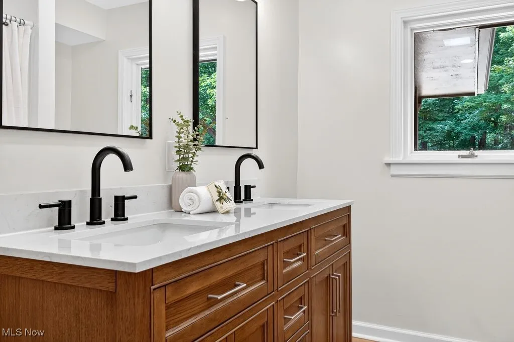 Full bathroom with double vanity and baseboards