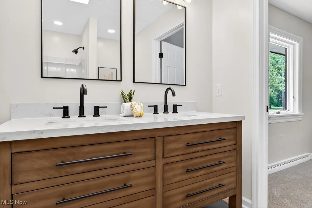 En-suite Bathroom with double vanity, a baseboard radiator, and a shower