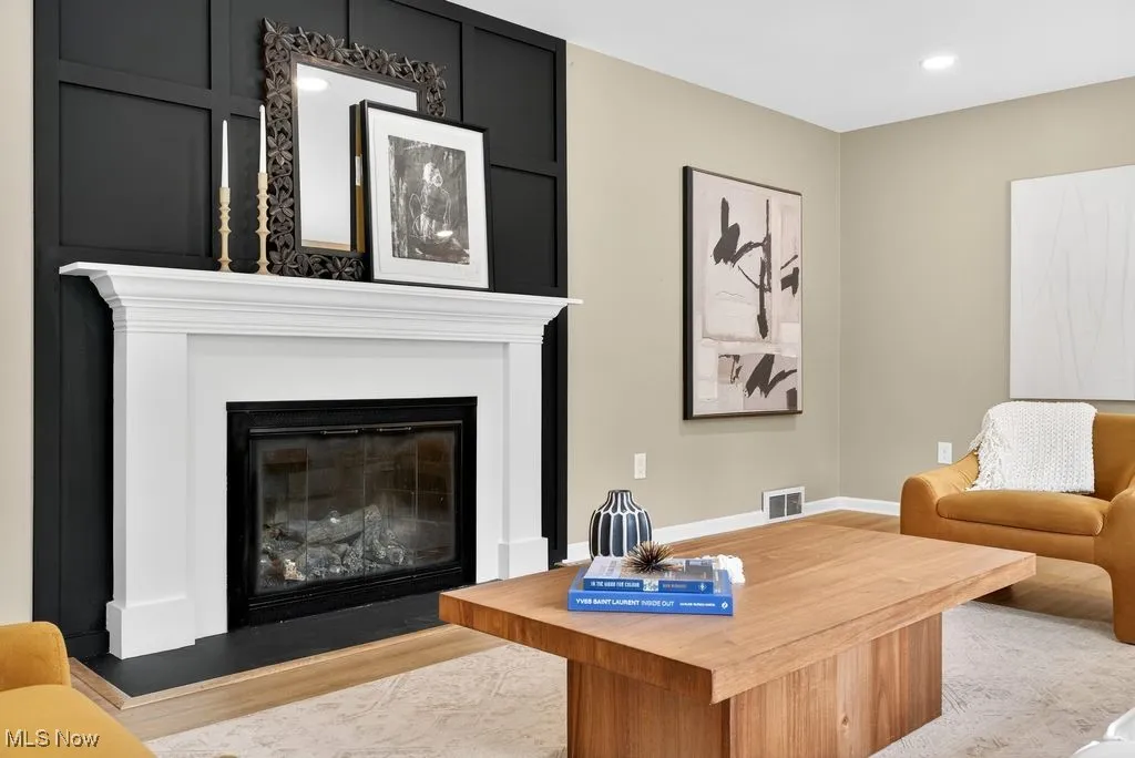 Living area featuring a glass covered fireplace, wood finished floors, and recessed lighting