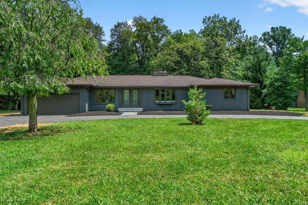 View of front facade with french doors, a front lawn, driveway, brick siding, and an attached garage