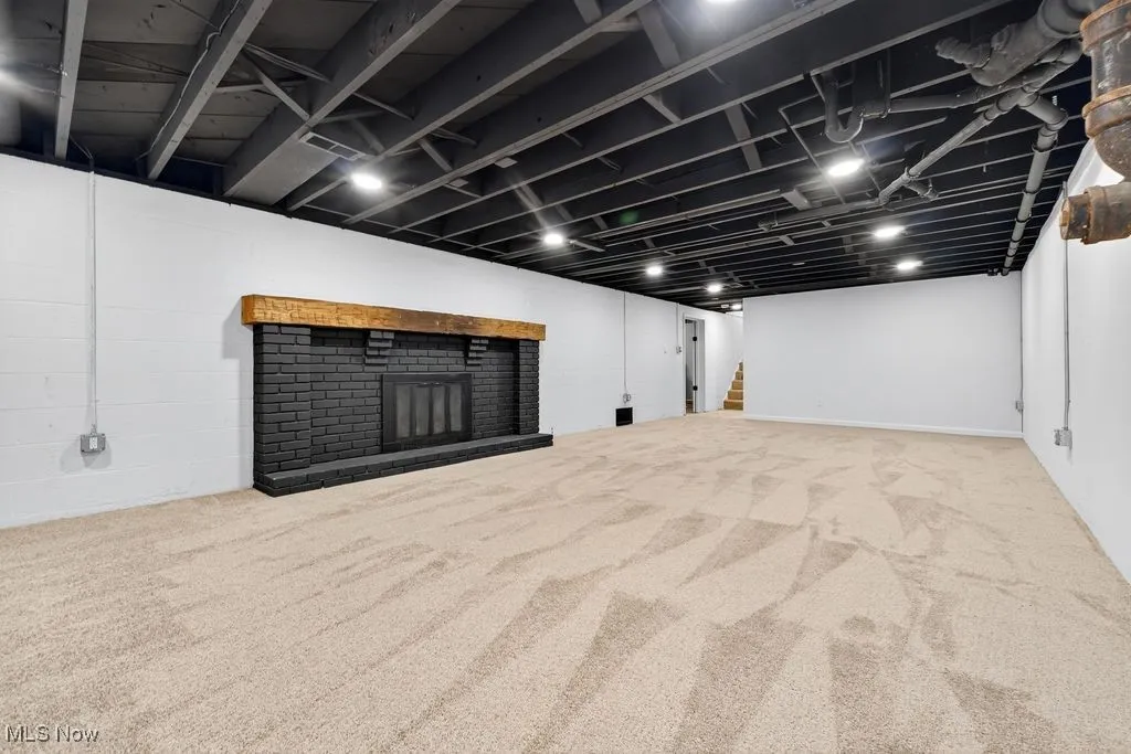 Finished below grade area featuring a fireplace, carpet floors, stairs, and concrete block wall