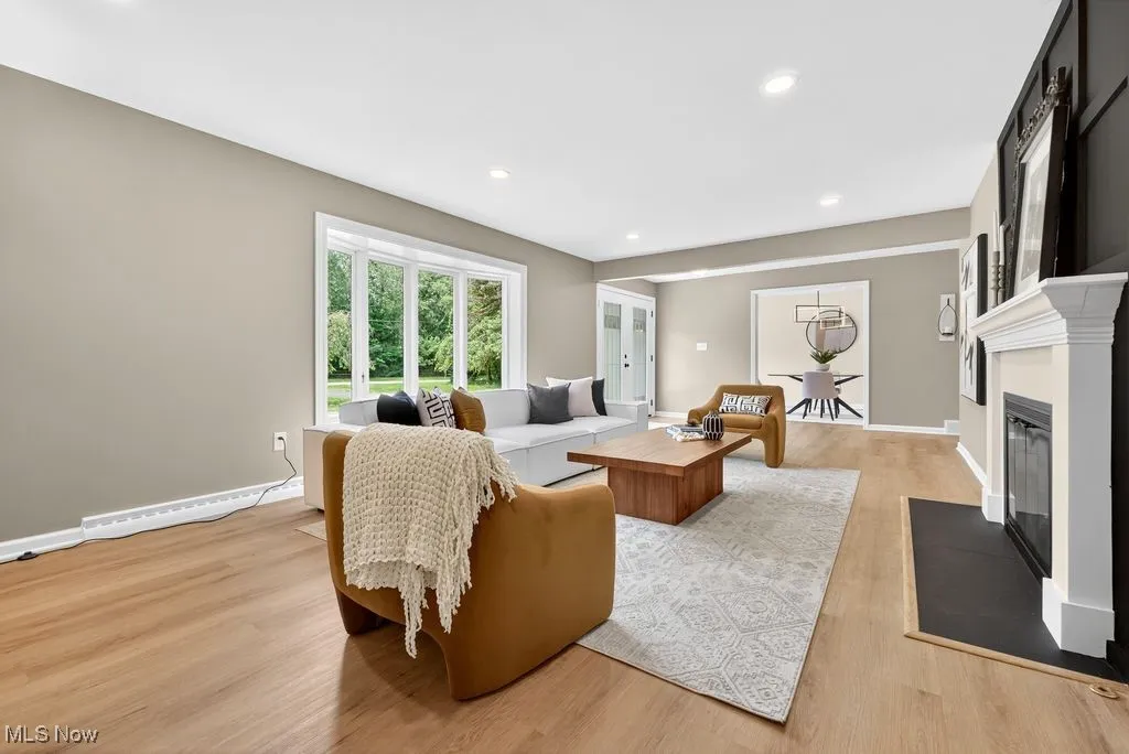 Living area with light wood finished floors, a fireplace with flush hearth, and recessed lighting
