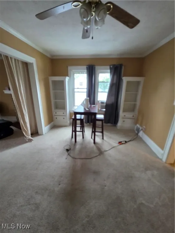 Dining space with light carpet, crown molding, and ceiling fan