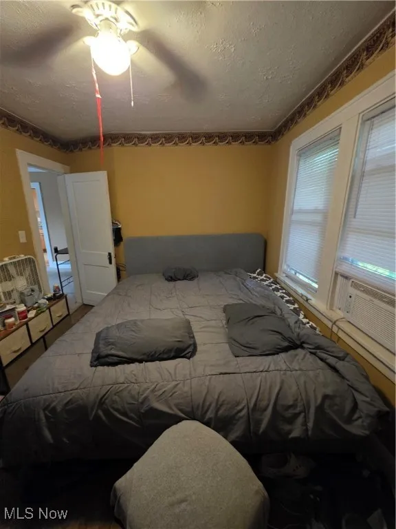 Bedroom featuring a textured ceiling, cooling unit, and ceiling fan