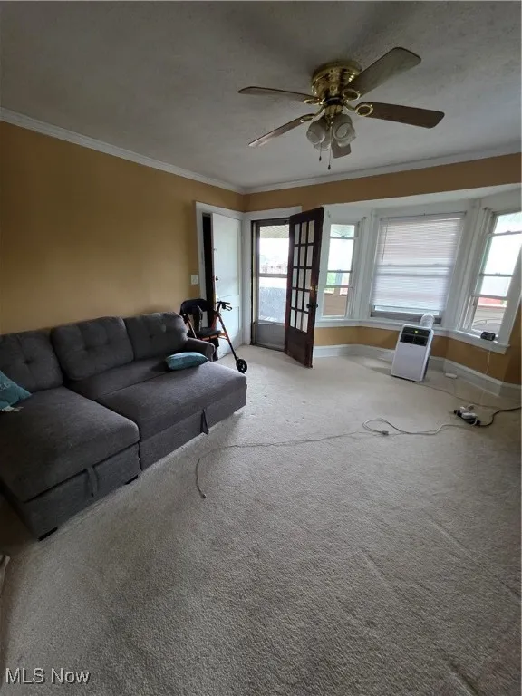 Living room with ornamental molding, carpet, ceiling fan, a textured ceiling, and french doors