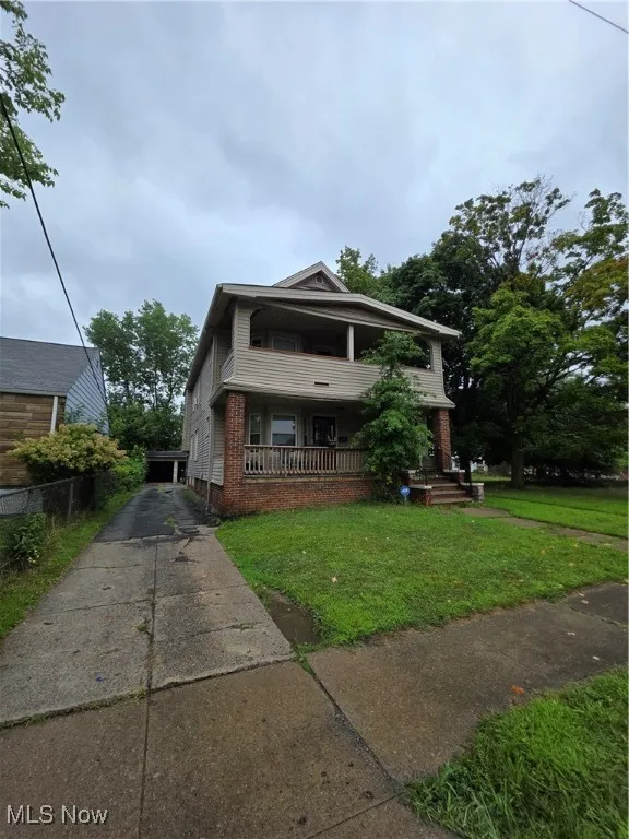 View of front facade with covered porch, brick siding, and driveway