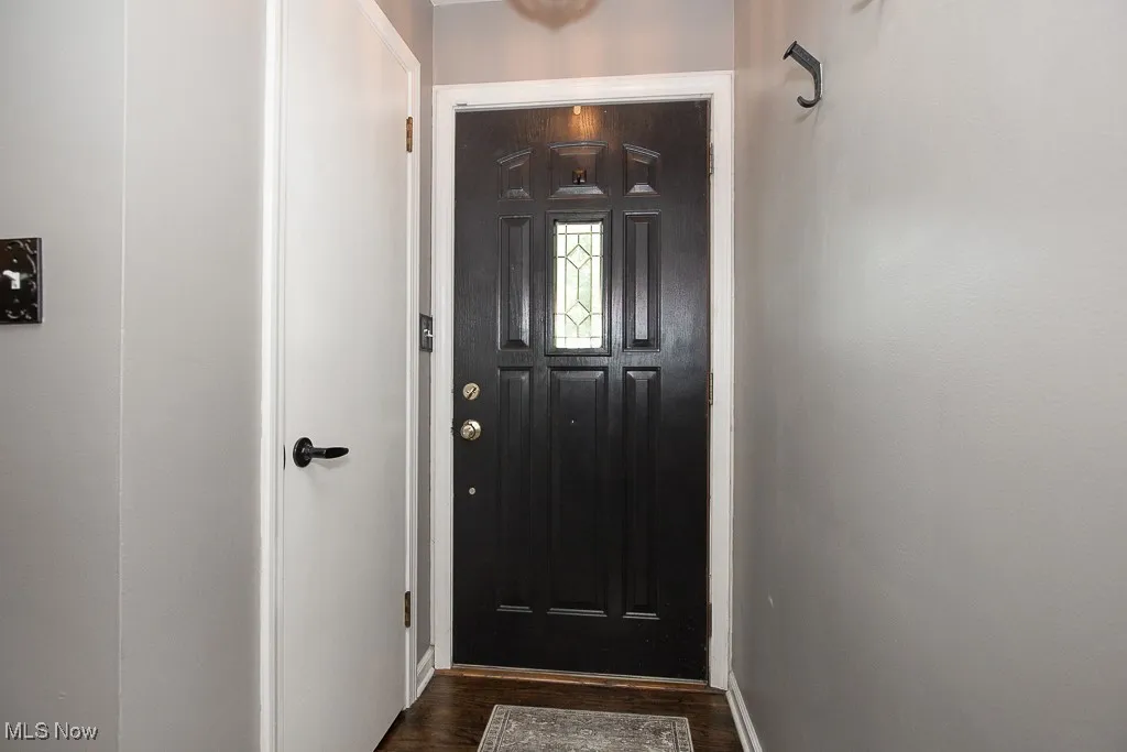 Doorway to outside with dark wood-type flooring and baseboards