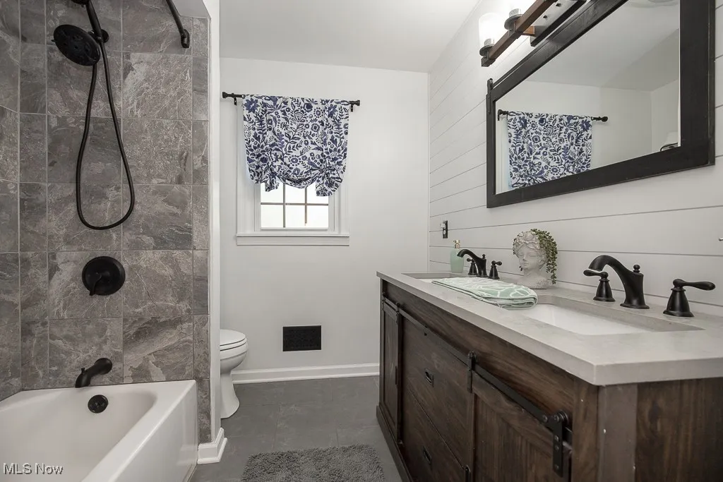 Bathroom featuring double vanity and shower / bath combo with shower curtain