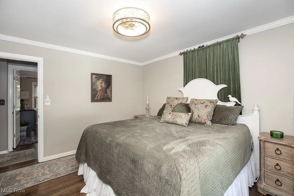 Bedroom with ornamental molding and dark wood finished floors