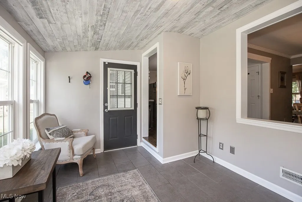Foyer with dark tile patterned floors and wooden ceiling