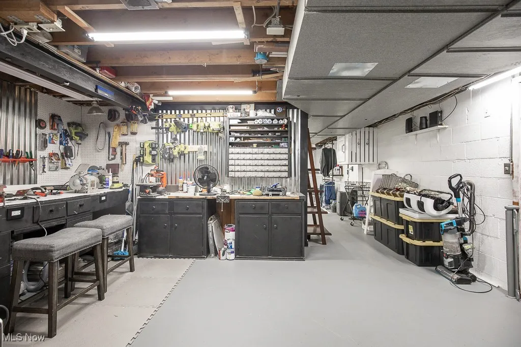 Miscellaneous room with finished concrete flooring, concrete block wall, and a workshop area