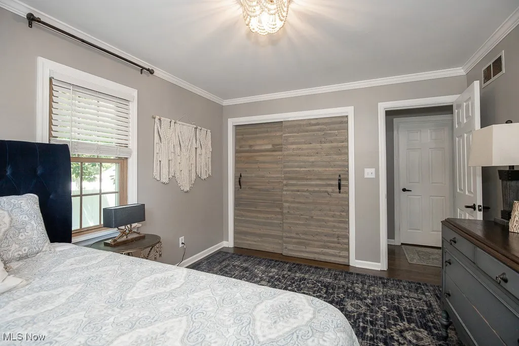 Bedroom featuring crown molding and dark wood-style floors