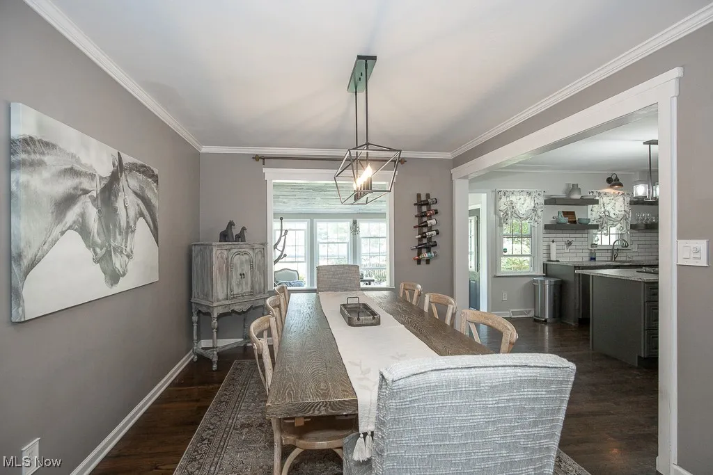 Dining area featuring dark wood finished floors, a chandelier, and ornamental molding