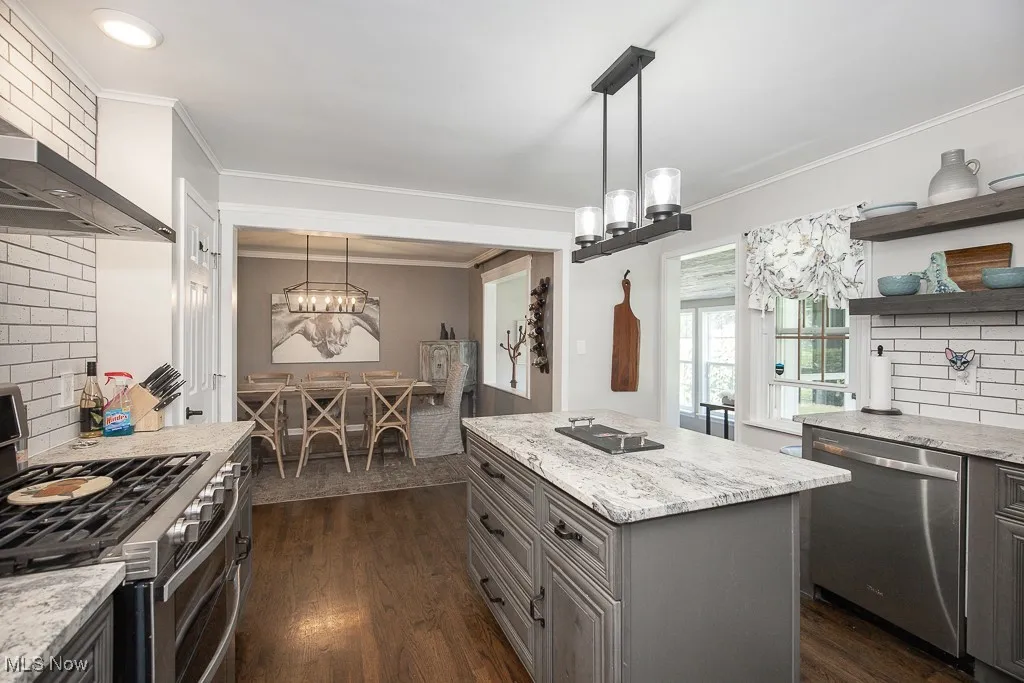 Kitchen featuring decorative backsplash, a chandelier, stainless steel appliances, ornamental molding, and gray cabinets