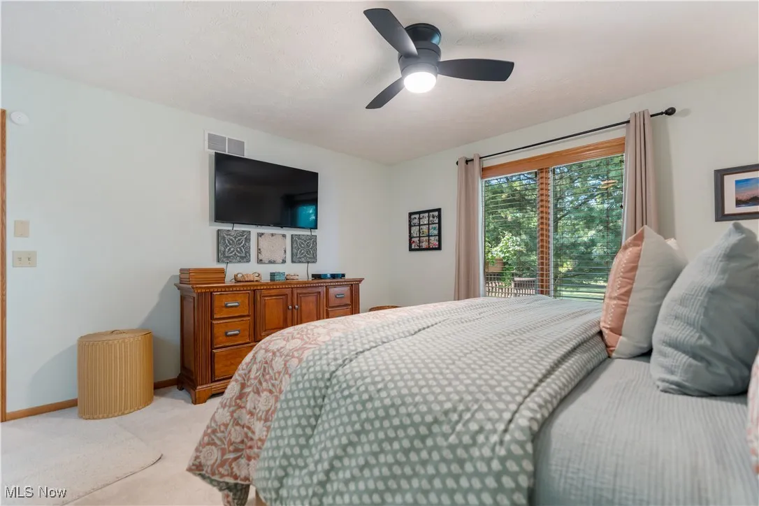Bedroom featuring light colored carpet, ceiling fan, and access to exterior