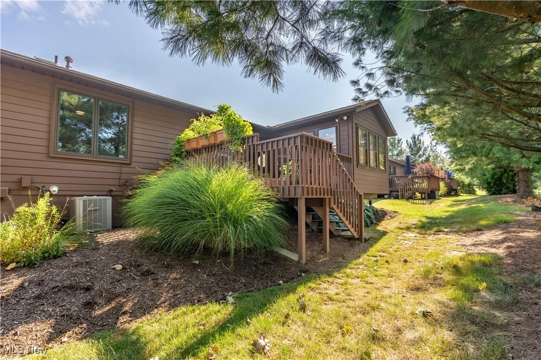 Back of house featuring stairs, a wooden deck, and a lawn