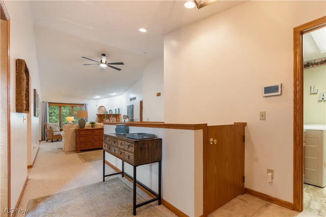 Hall featuring vaulted ceiling, recessed lighting, washer / dryer, and light colored carpet