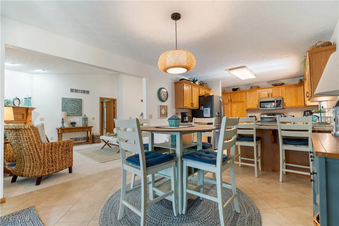 Dining area with a textured ceiling, lofted ceiling, and light tile patterned flooring