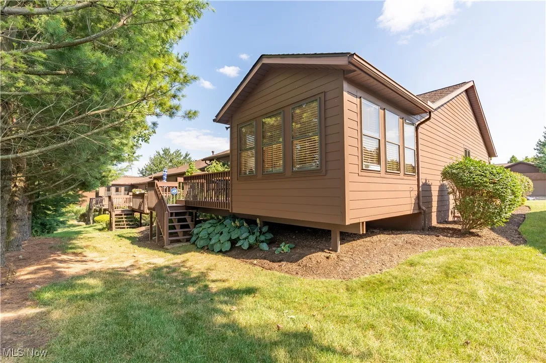 View of home's exterior with a wooden deck, stairway, and a yard