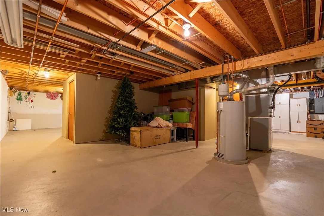 Unfinished basement featuring water heater, electric panel, and heating unit