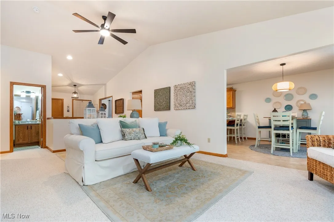 Living area with vaulted ceiling, light colored carpet, recessed lighting, and a ceiling fan