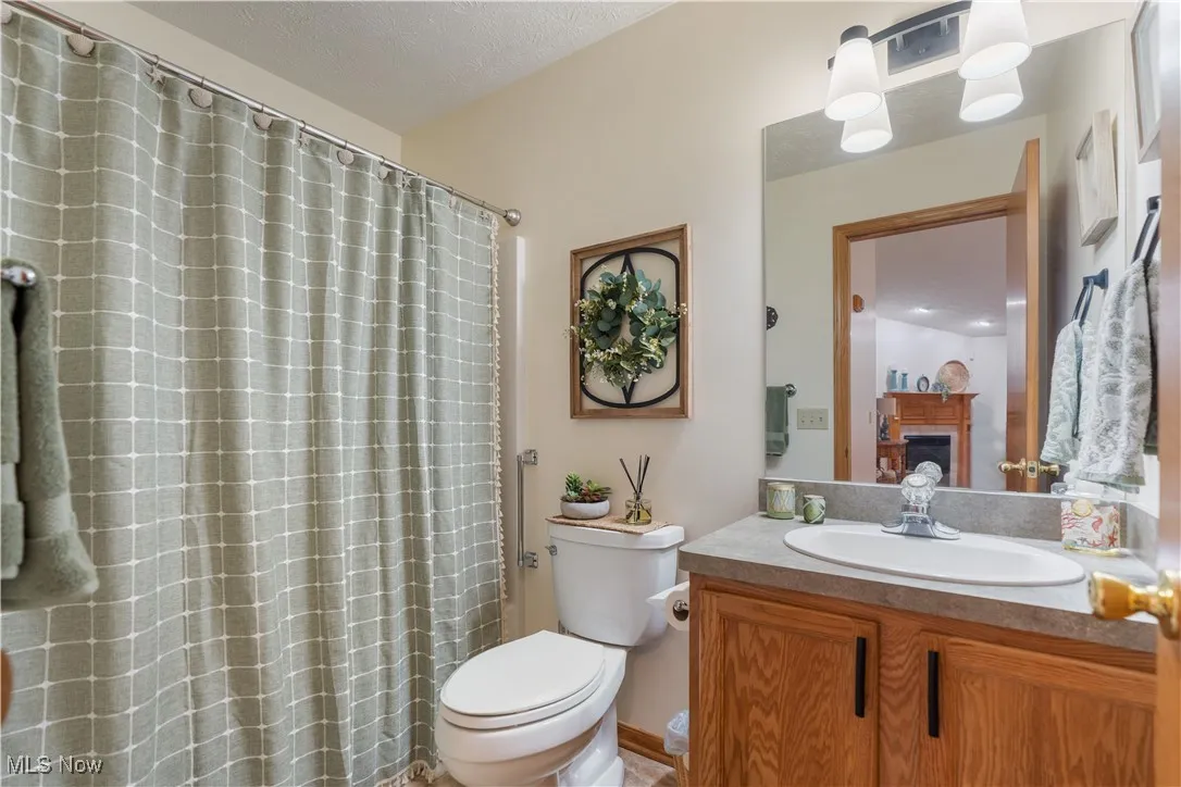Bathroom with vanity, a fireplace, a textured ceiling, and a shower with curtain