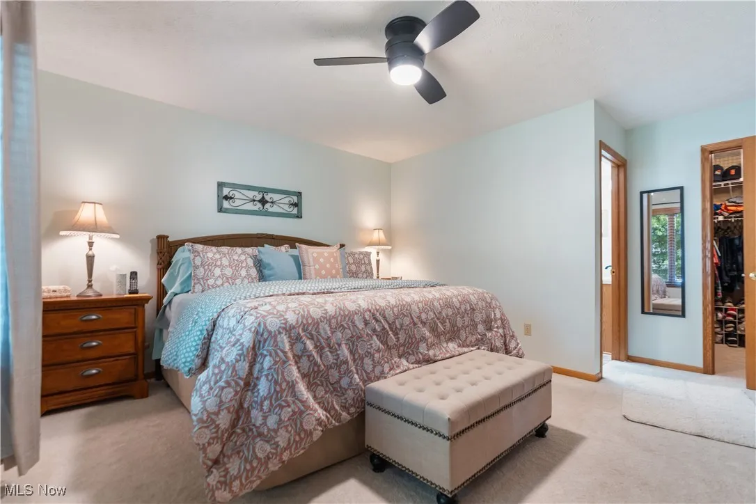 Carpeted bedroom featuring a walk in closet, ceiling fan, and a textured ceiling