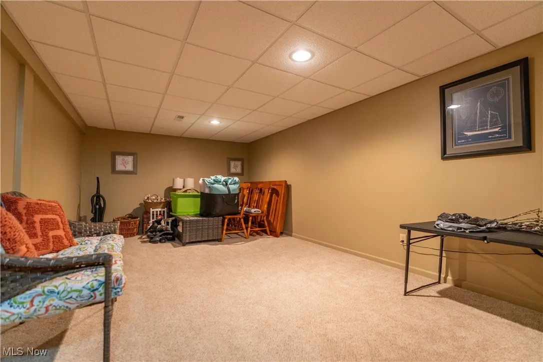 Living area featuring a drop ceiling, carpet flooring, and recessed lighting