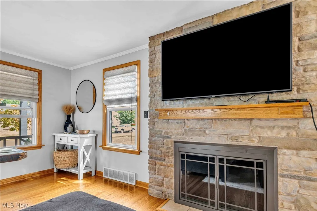 Living area featuring wood finished floors, crown molding, a fireplace, and plenty of natural light