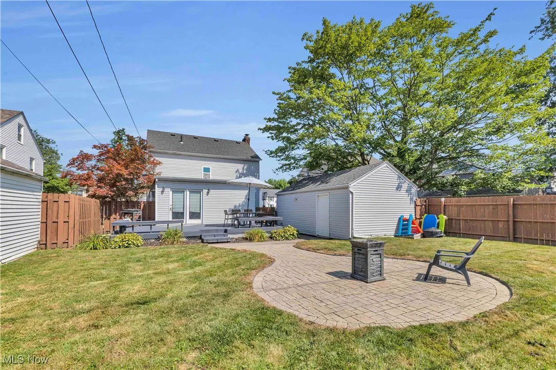 Back of property featuring a patio, a fenced backyard, a deck, a shed, and a chimney