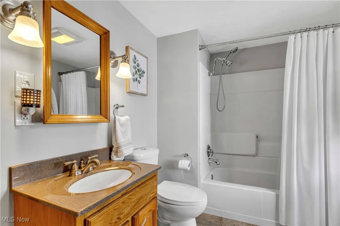 Full bath with vanity, shower / bath combo, and tile patterned flooring