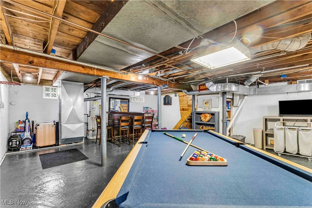 Rec room with pool table, heating unit, a bar, finished concrete floors, and gas water heater