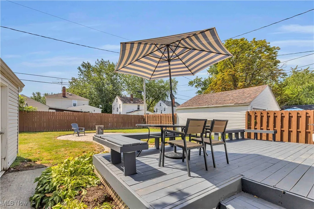 Wooden terrace with outdoor dining area and a fenced backyard