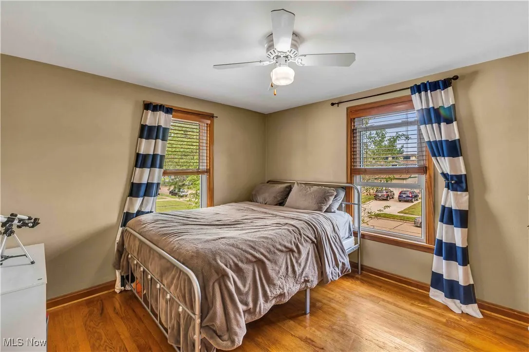 Bedroom with wood finished floors, multiple windows, and ceiling fan