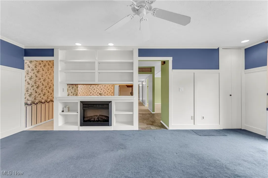 Unfurnished living room with a wainscoted wall, recessed lighting, ceiling fan, a fireplace, and carpet flooring