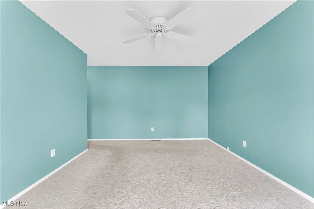 Unfurnished room with a ceiling fan and carpet flooring
