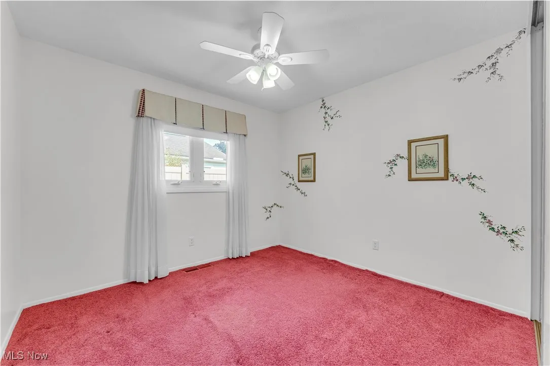 Carpeted empty room featuring a ceiling fan and baseboards