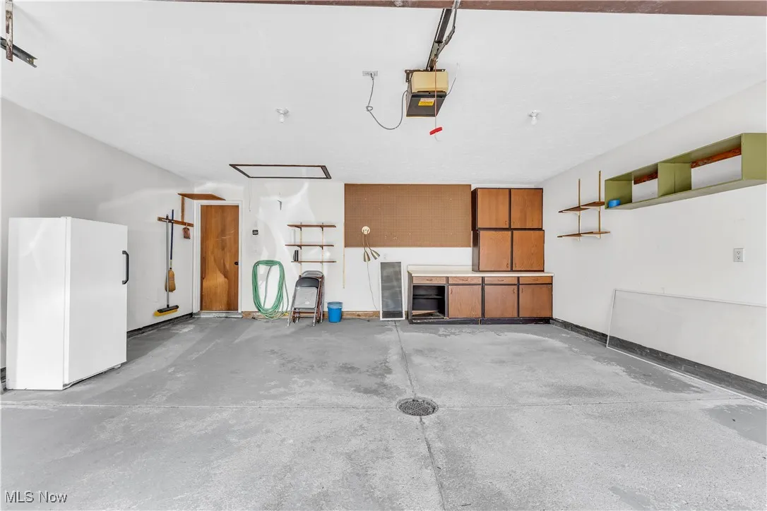 Garage featuring freestanding refrigerator and a garage door opener
