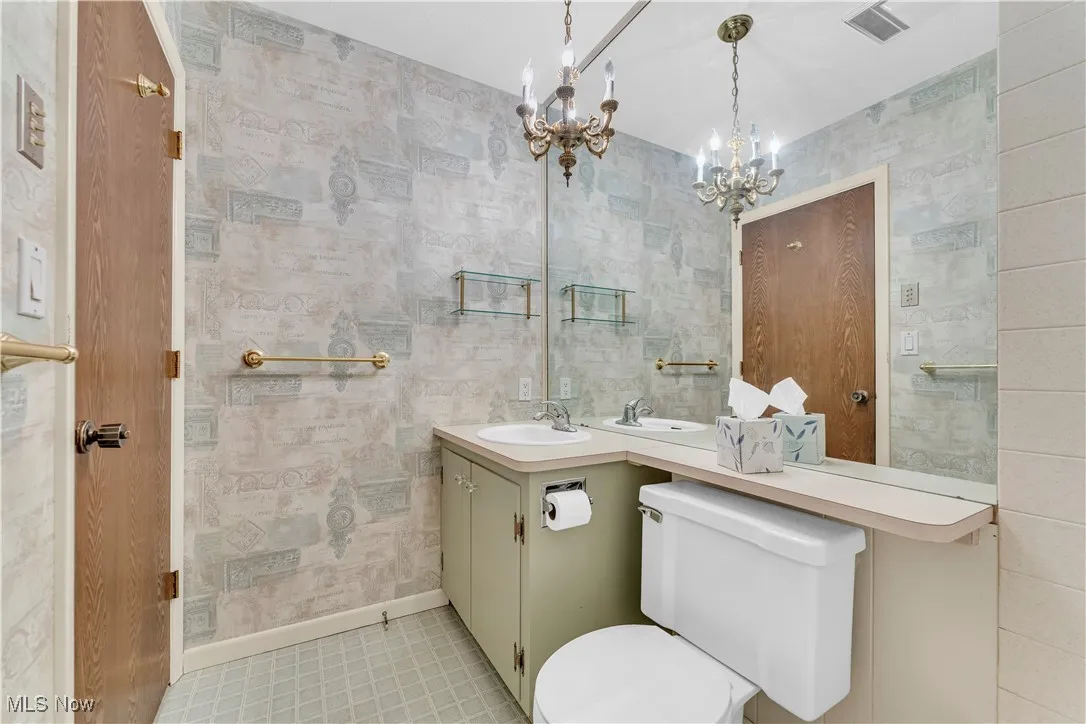Bathroom featuring vanity, a chandelier, and wallpapered walls