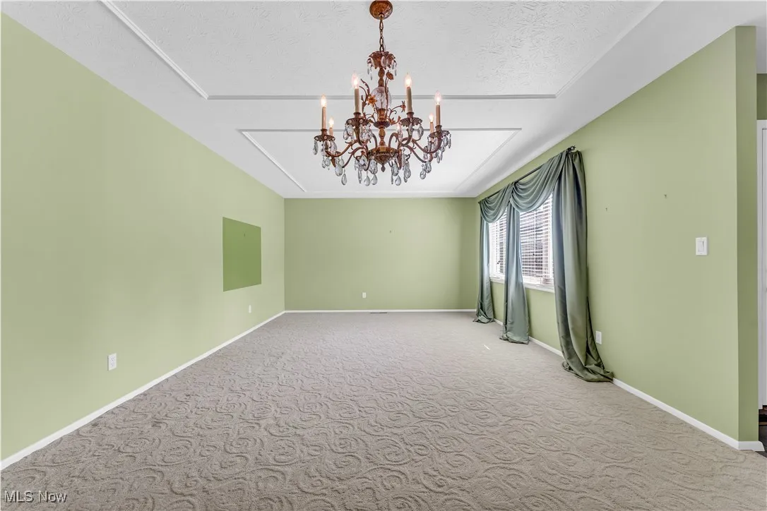 Unfurnished room with carpet, a chandelier, and a textured ceiling