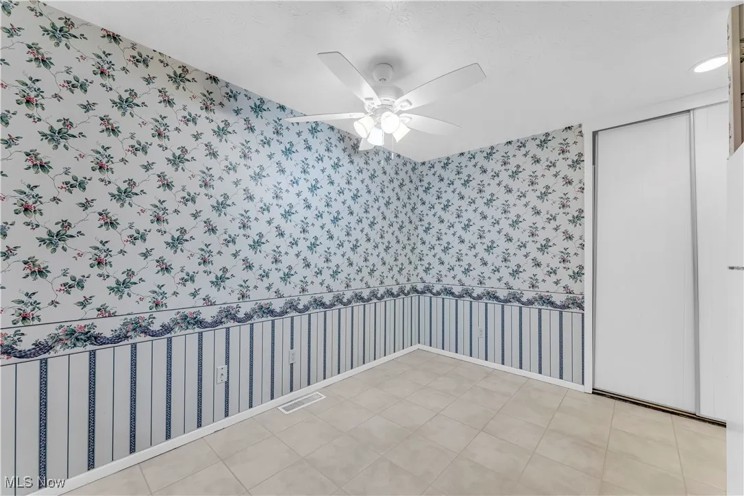 Unfurnished room with wallpapered walls and a ceiling fan