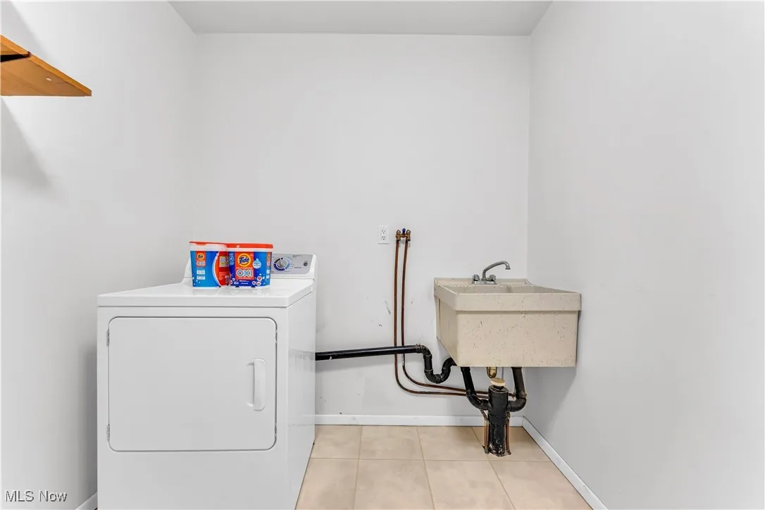 Washroom with washer / clothes dryer and light tile patterned flooring