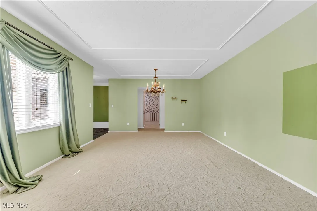 Unfurnished room featuring a chandelier and carpet floors