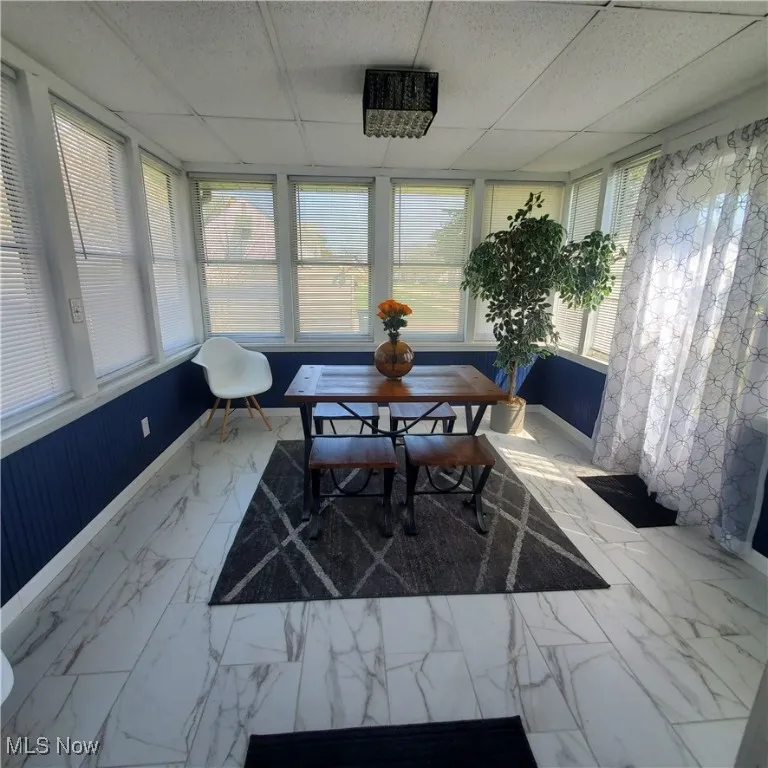 Sunroom with a paneled ceiling and marble look tiles