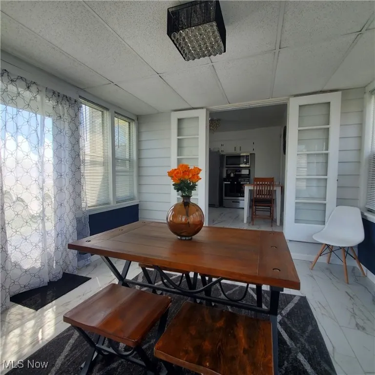 Dining area with a drop ceiling, built in features, and marble finish floors