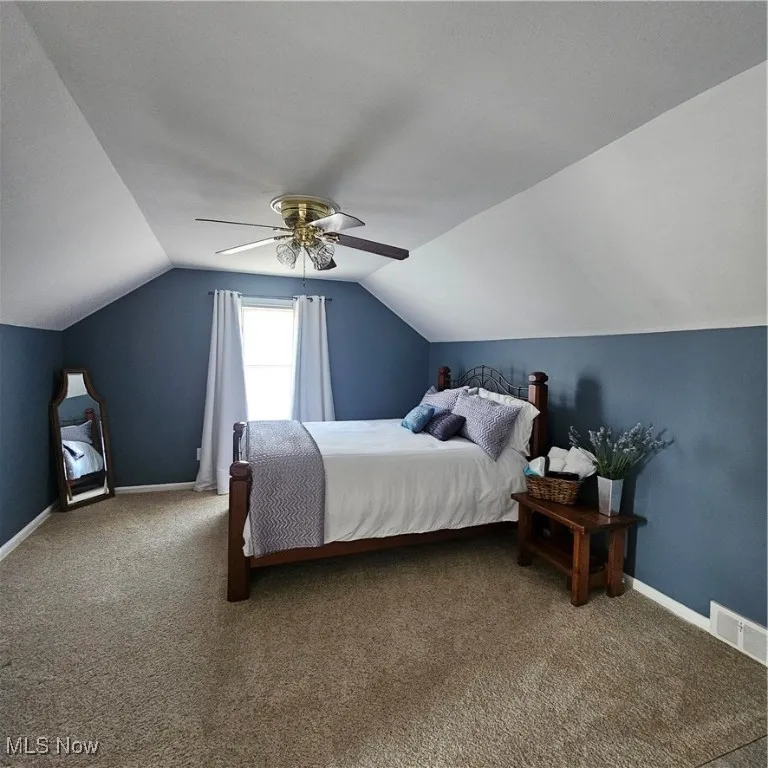 Carpeted bedroom with lofted ceiling and a ceiling fan