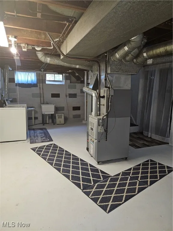 Below grade area featuring heating unit and washing machine and clothes dryer