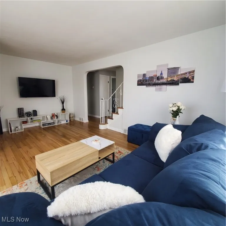 Living room featuring arched walkways, wood finished floors, and stairs