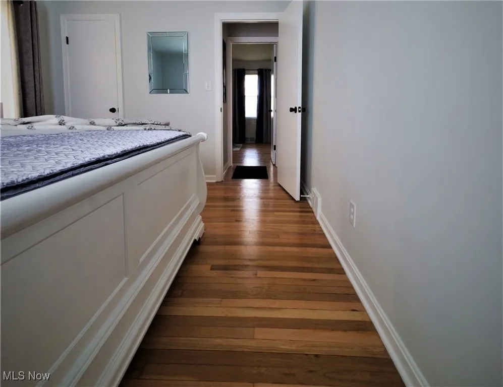 Corridor featuring baseboards and dark wood-type flooring