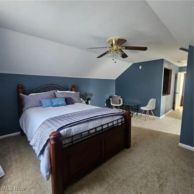 Bedroom featuring light colored carpet, vaulted ceiling, and ceiling fan